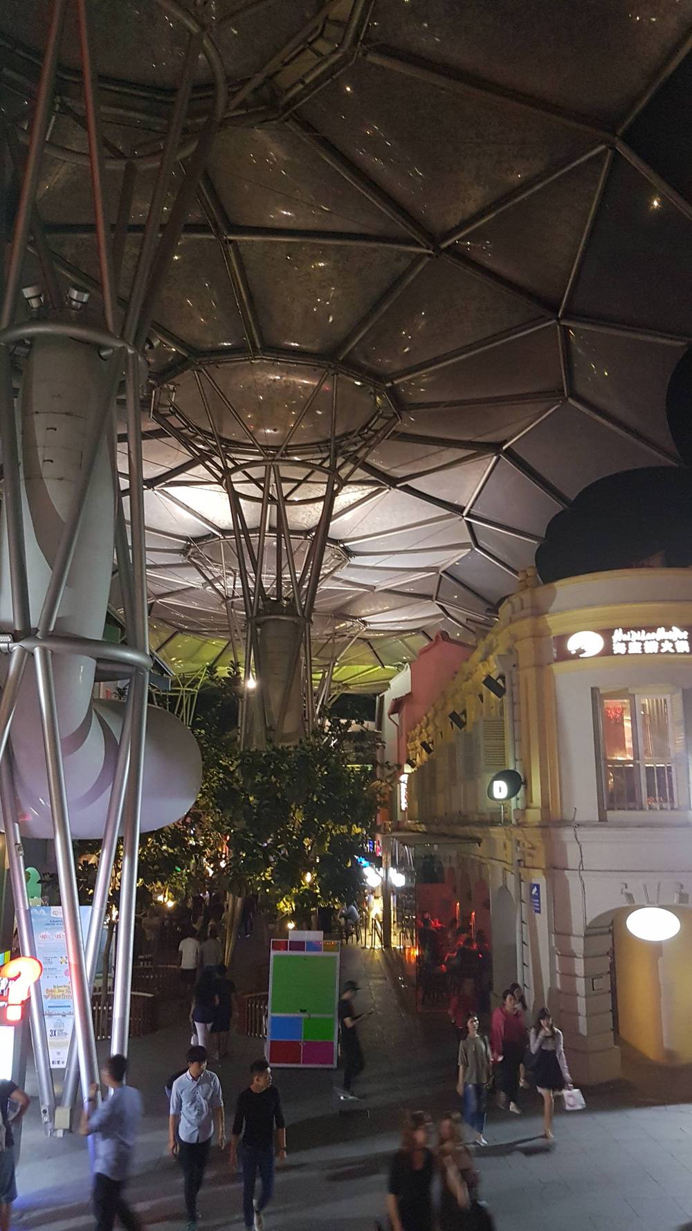 Another decorative canopy structure is lit up over the plaza at night.