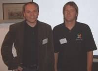 Two men stand side by side wearing name badges at a conference.
