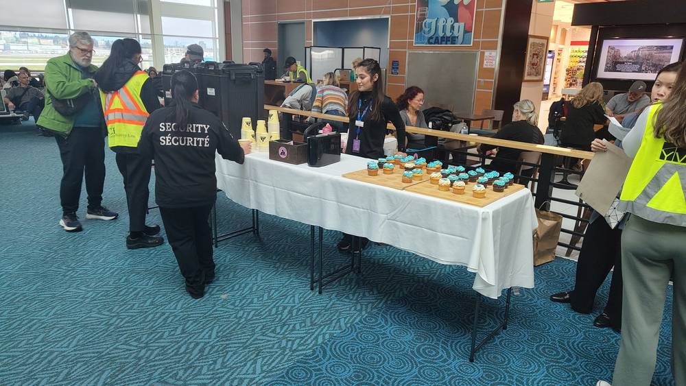 Security staff and a refreshment table set up in an airport terminal.