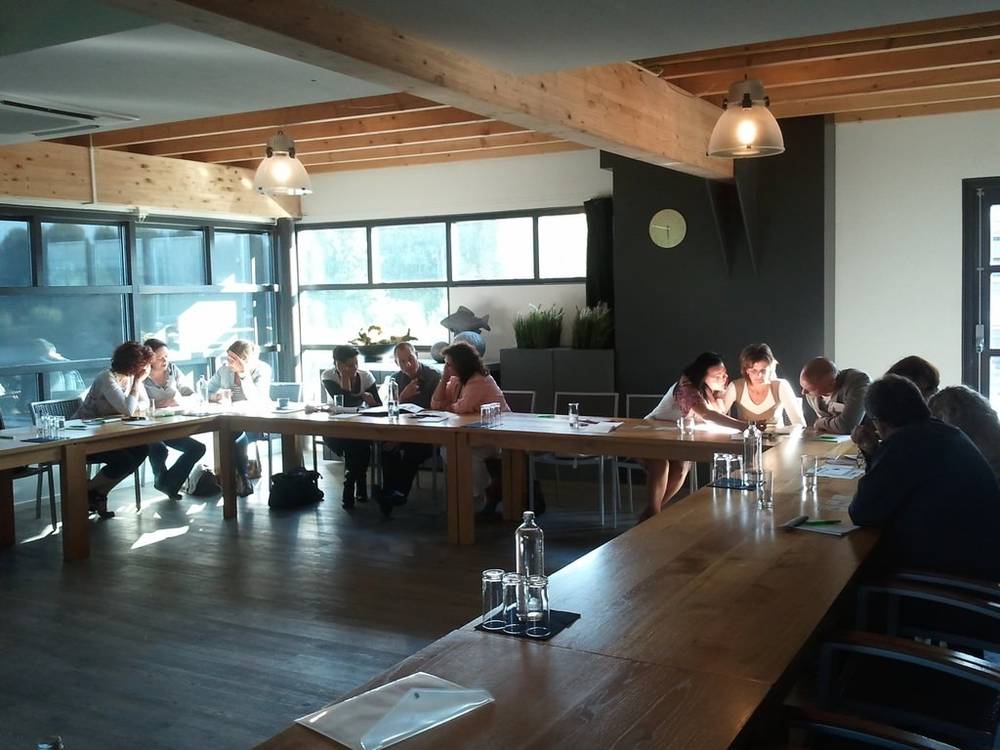 A group sits around a long wooden table during a business meeting.