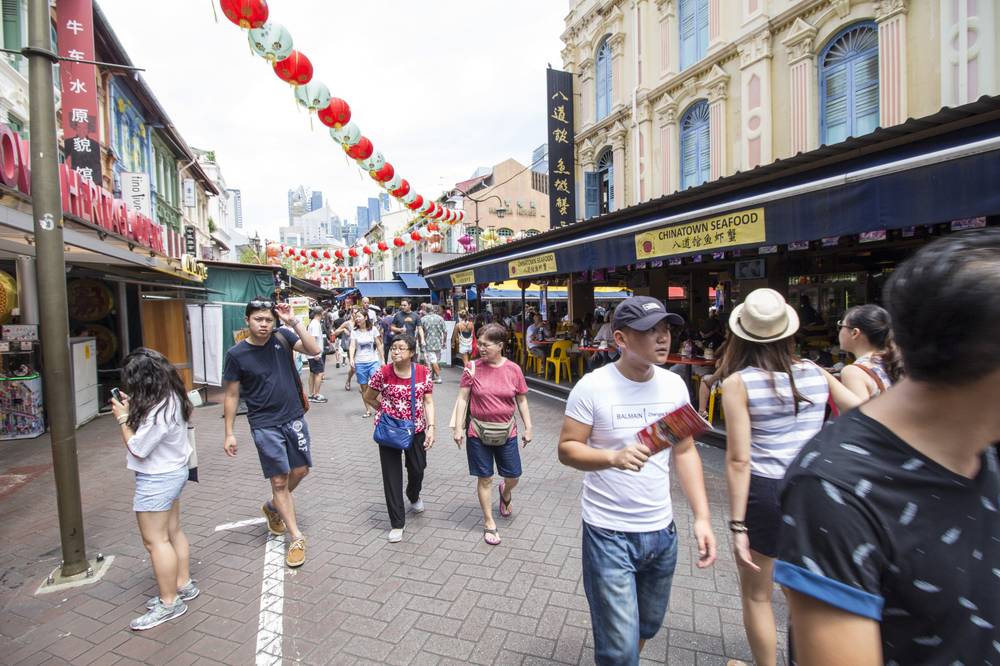 Another Chinatown street with red lanterns and heritage shophouses, crowded with walkers.