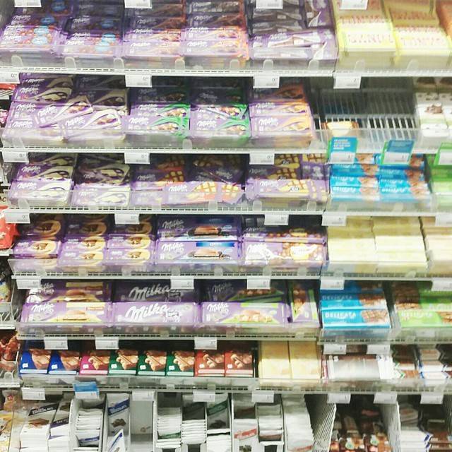 Supermarket shelves stocked with rows of chocolate bars, including Milka.