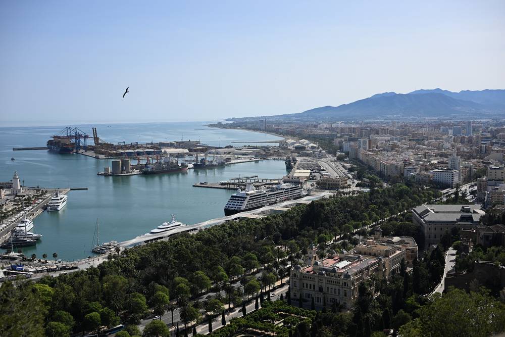 An overview of the port of Malaga with mountains in the back from the view of a flying seagull