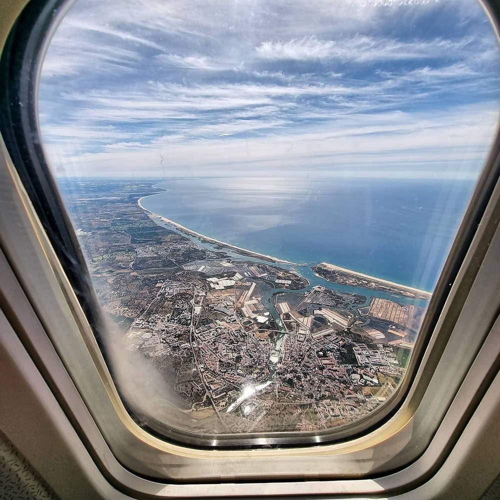 View through an airplane window of a coastal city and harbor from high altitude.