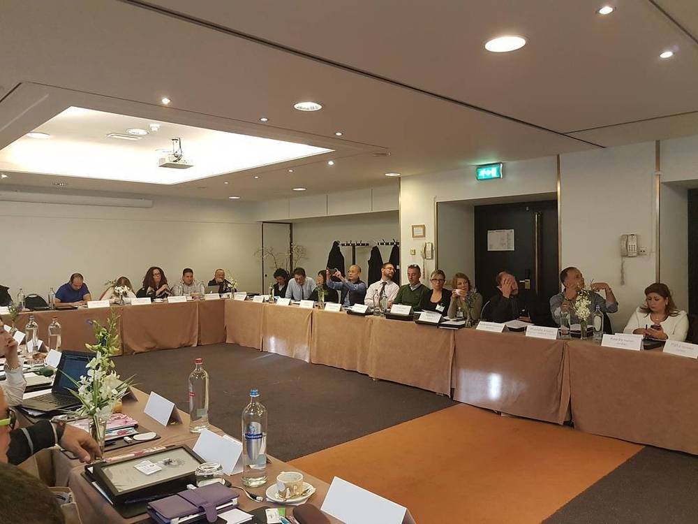 A group of people seated around a large conference table during a meeting.