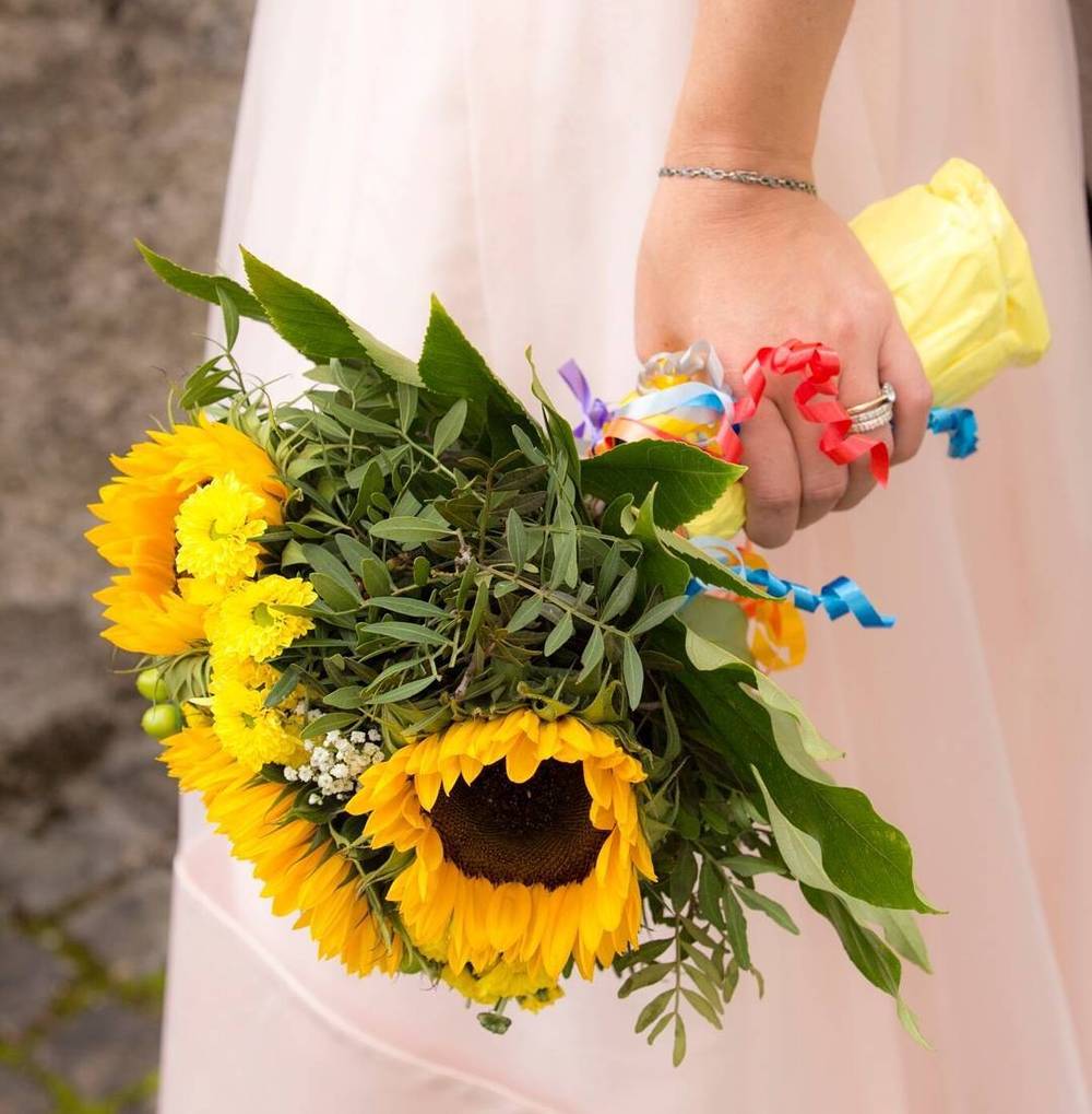 A bride holding a sunflower bouquet against her pink dress.