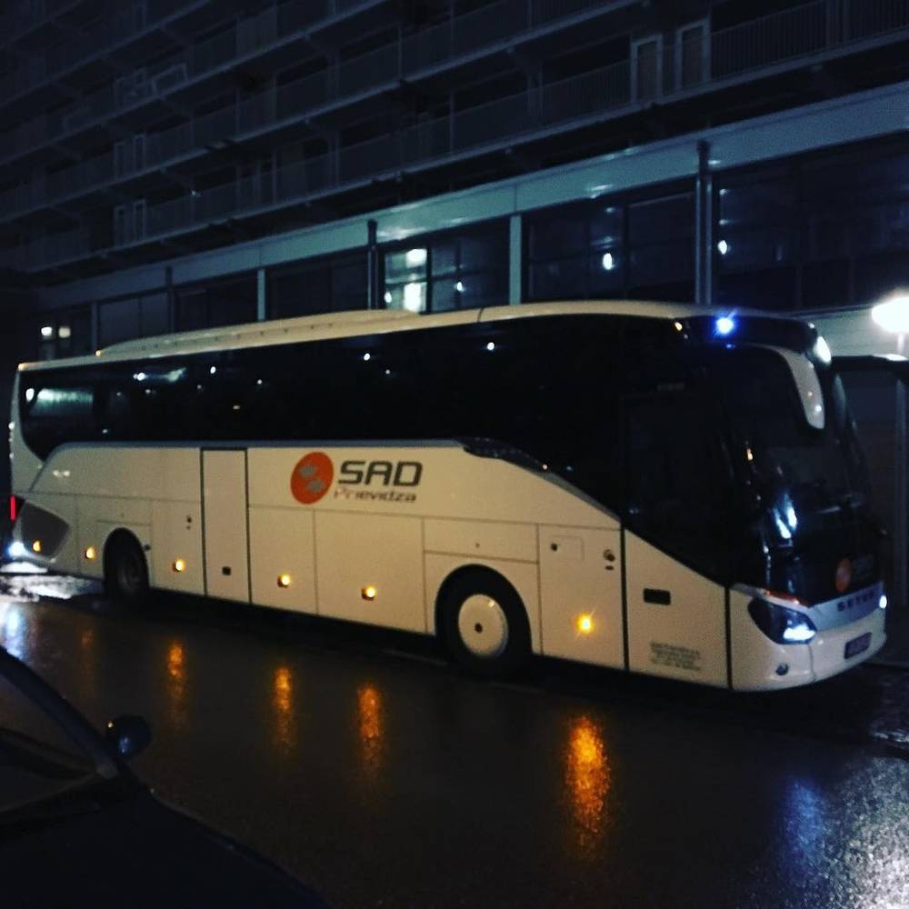 A coach bus parked outside an apartment building at night.