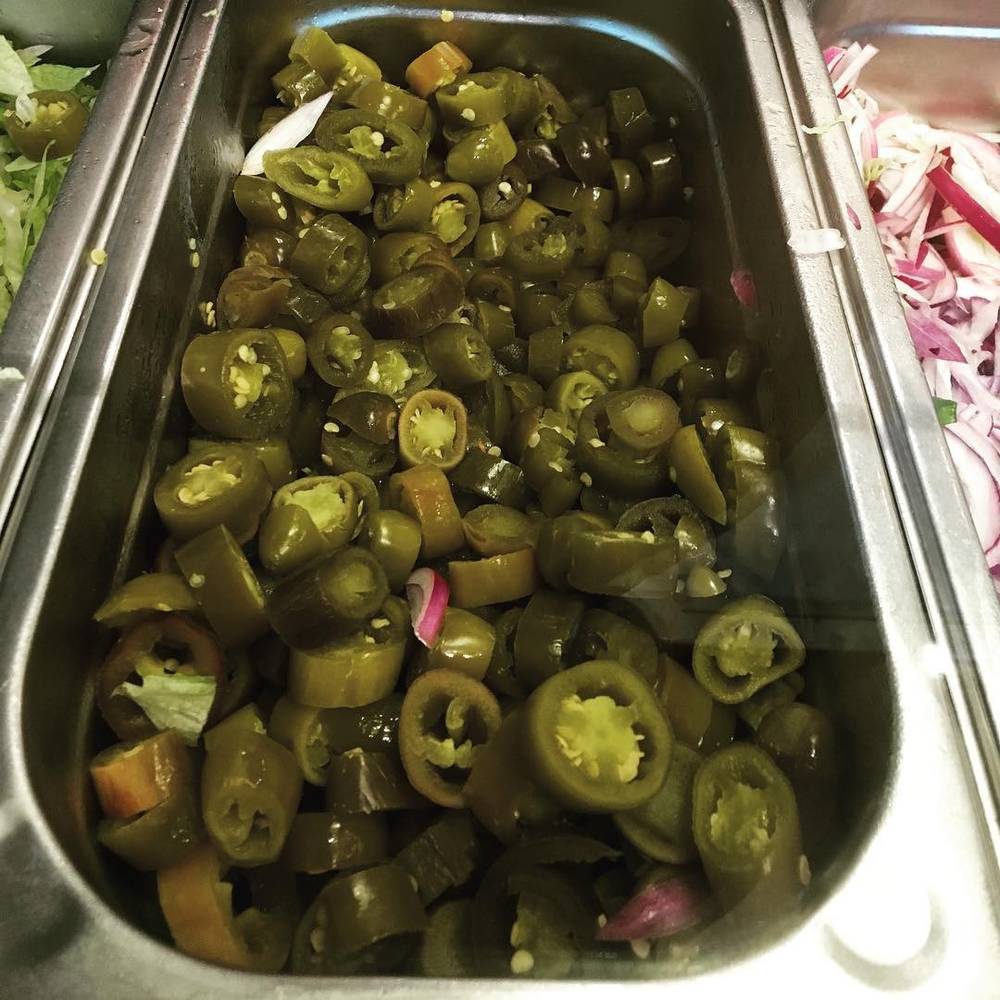 A tray of sliced jalapeno peppers in a buffet container.