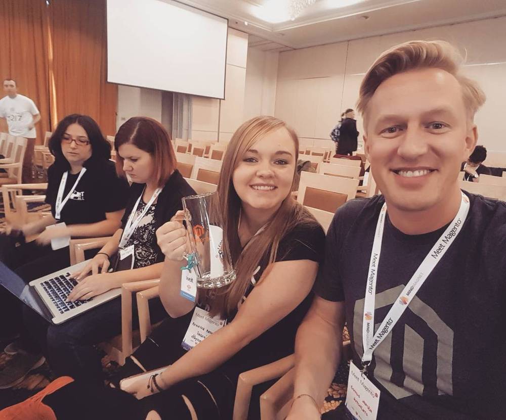 Selfie with colleagues at a conference, one holding up a small trophy.