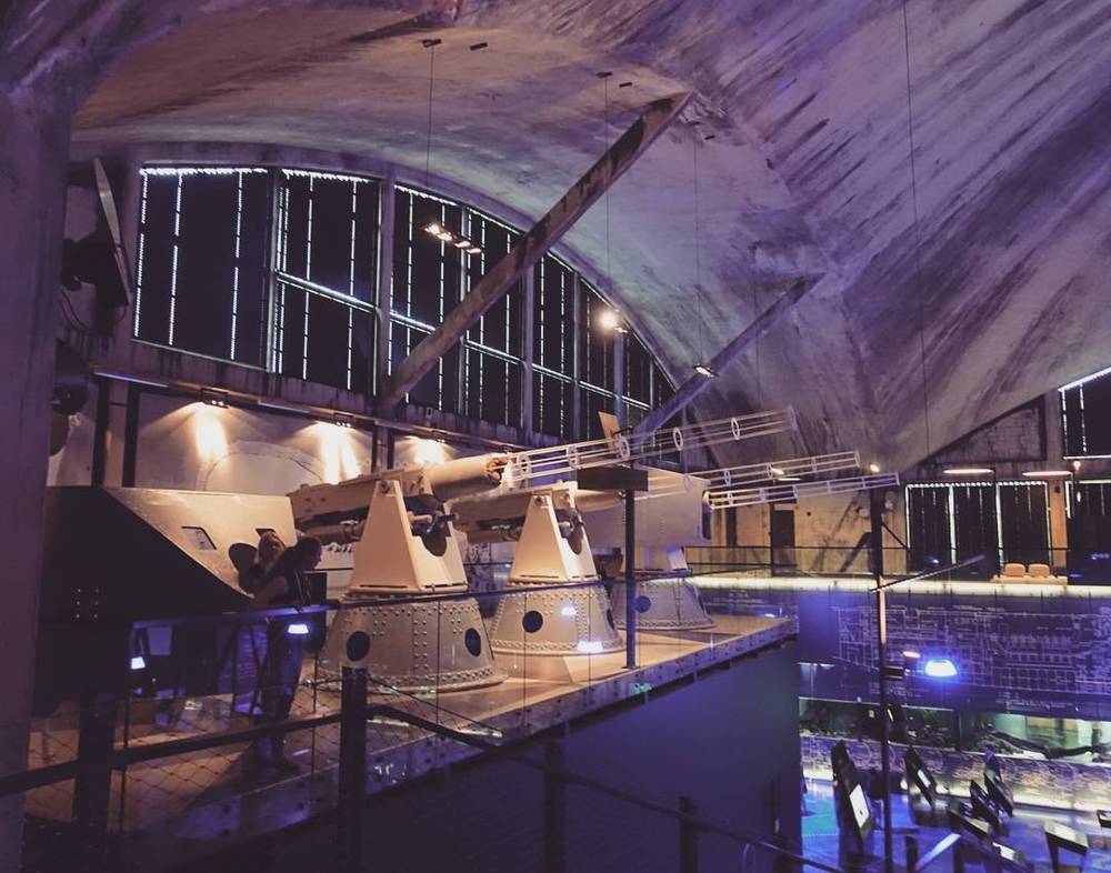 A museum hall displaying space capsule mock-ups under a curved, illuminated ceiling.