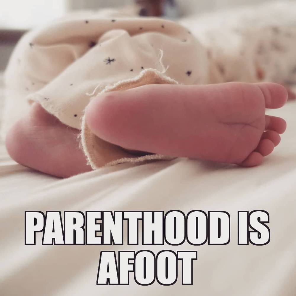 Close-up of a newborn's foot wrapped in a blanket, with text overlay reading "Parenthood is afoot".