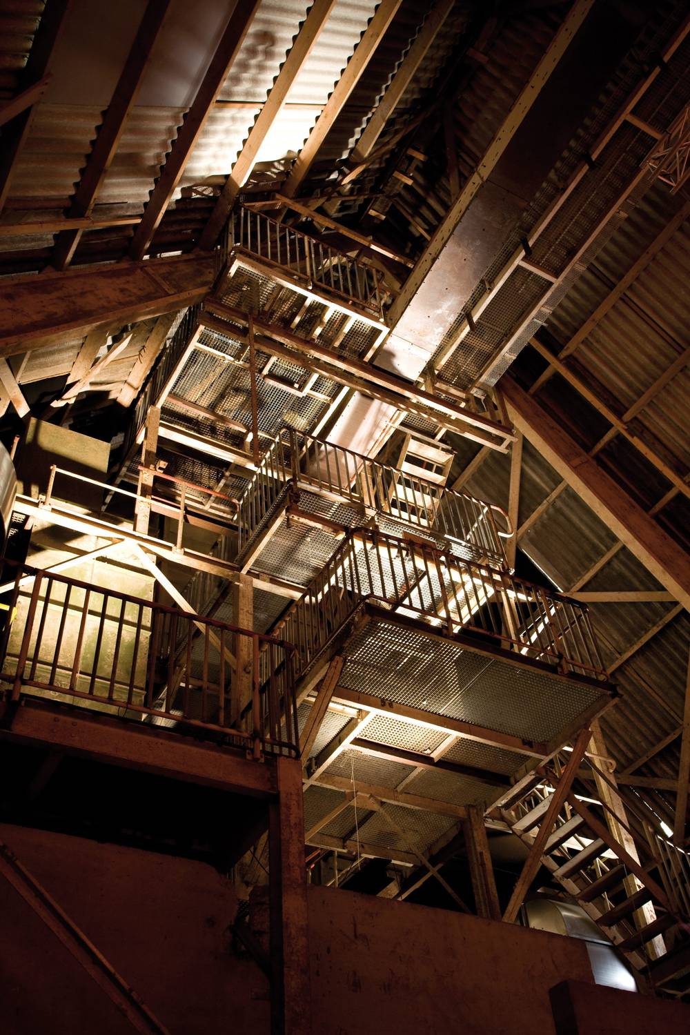 Steel scaffolding and staircases fill the dim, cavernous attic of an industrial building.