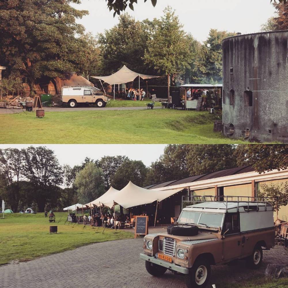 An outdoor event with a stretch tent and a Land Rover parked on the grass at dusk.