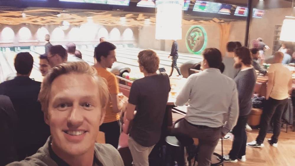 Selfie at a bowling alley with people playing in the background.