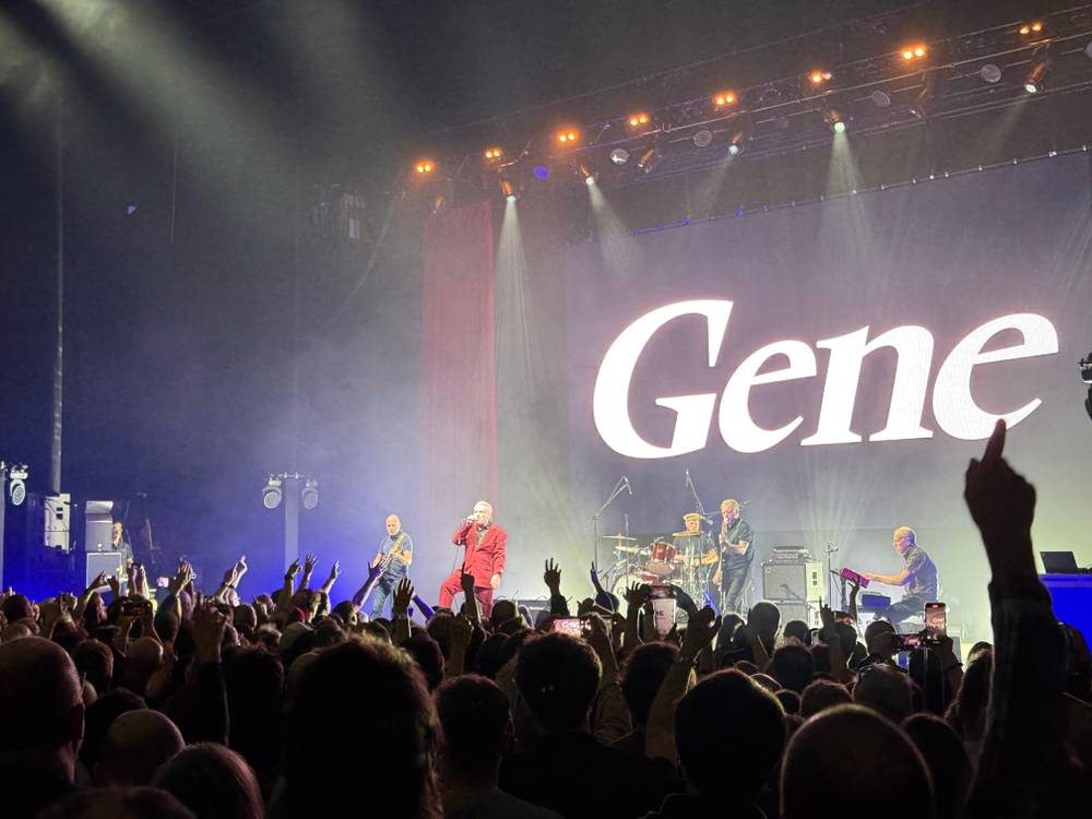 Gene on stage: man in red suit with "Gene" in background