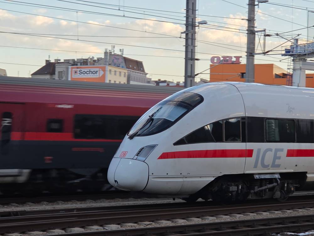 Two trains rolling next to each other. Behind is the ÖBBRailJet in its red/black livery. The white train in front is a German Intercity-Express (ICE) from the ICE T