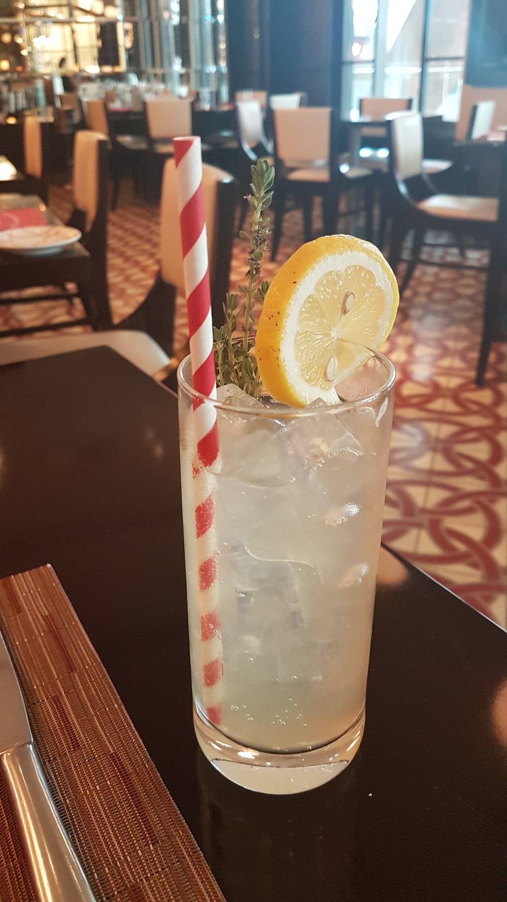 A glass of iced tea garnished with a lemon slice on a restaurant table.