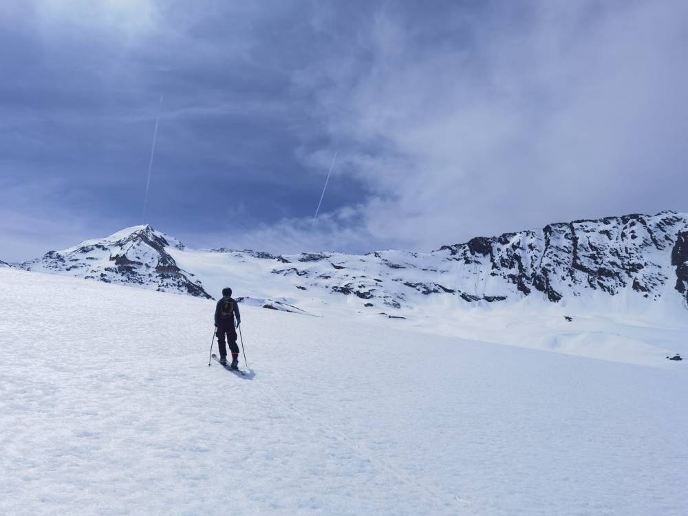 Skier hiking toward a distant glacier (Géfret glacier)