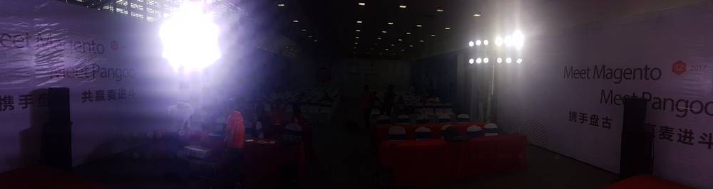 A dark exhibition hall is lit by bright stage lights under a 'Meet Pangoo' sign.