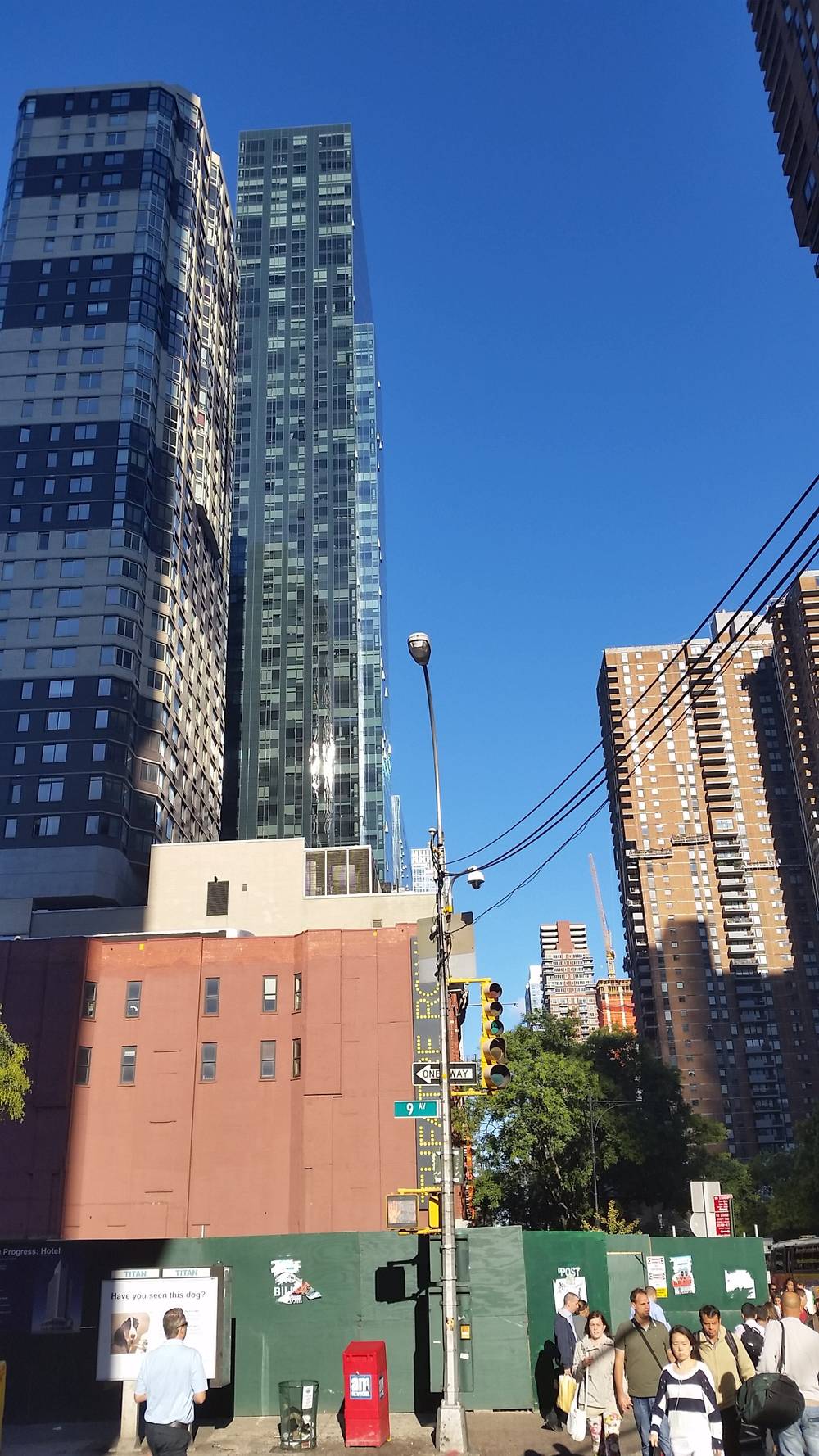 A sunny Manhattan street corner is lined with apartment buildings.