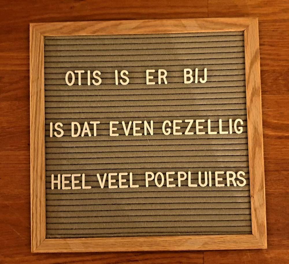 A wooden letterboard reads "Otis is er bij, is dat even gezellig, heel veel poepluiers" about a new baby.