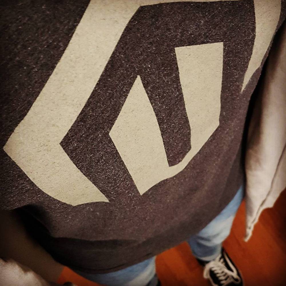 Close-up of a geometric logo printed on a grey t-shirt.
