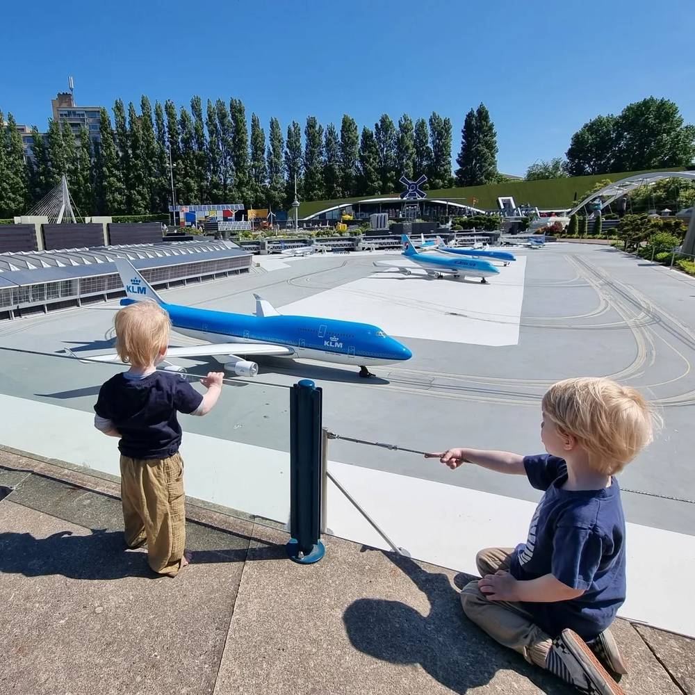 Two children looking at miniature KLM airplanes on a model airport runway at Madurodam.