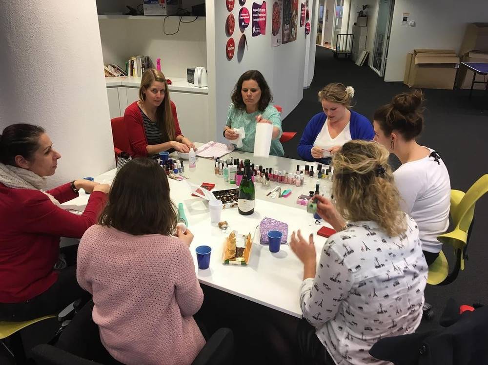 A group of women doing a manicure workshop together around a table.