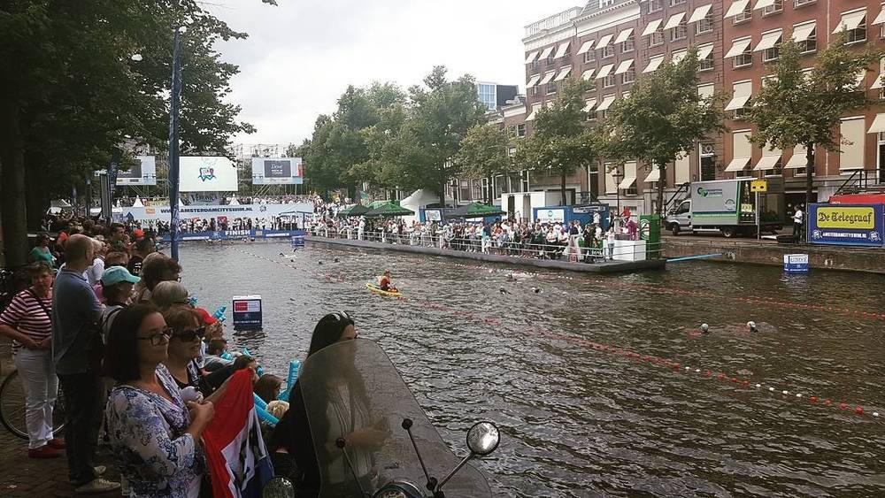 Spectators along an Amsterdam canal watching swimmers during the Amsterdam City Swim event.