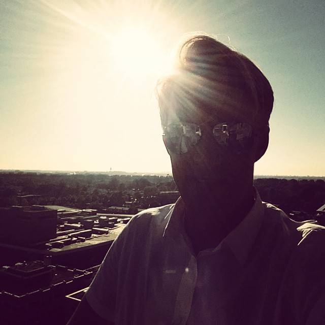 Silhouette of a man against bright sunlight, overlooking a cityscape.