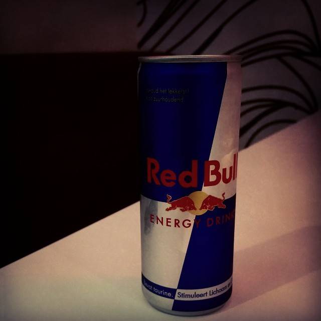 A can of Red Bull energy drink on a dark table.