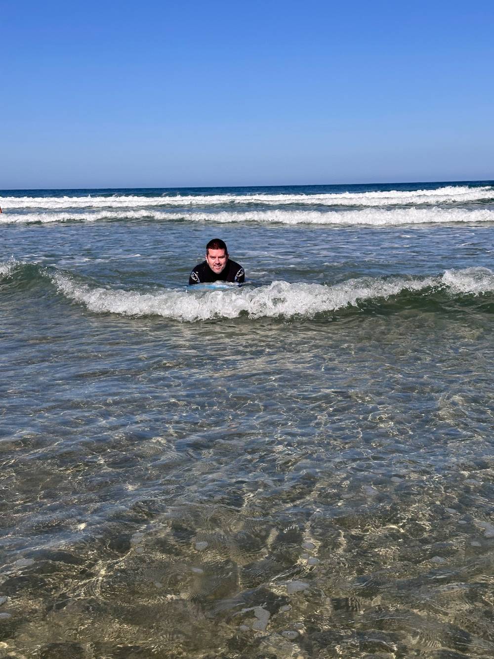Man in wetsuit lying on a bodyboard on a beach