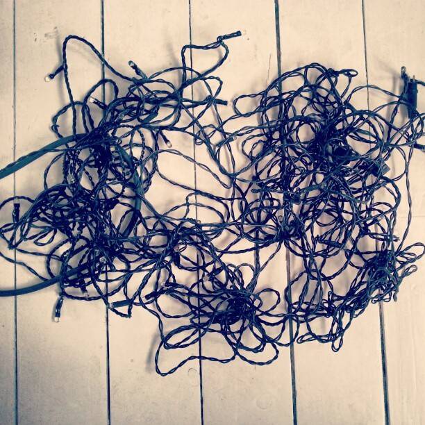 A tangled mass of blue string lights laid out on a wooden deck.