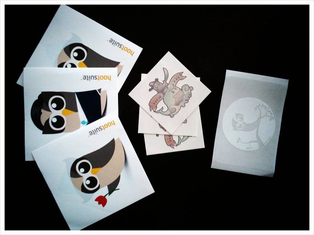 Small owl-themed Hootsuite stickers laid out on a dark surface.