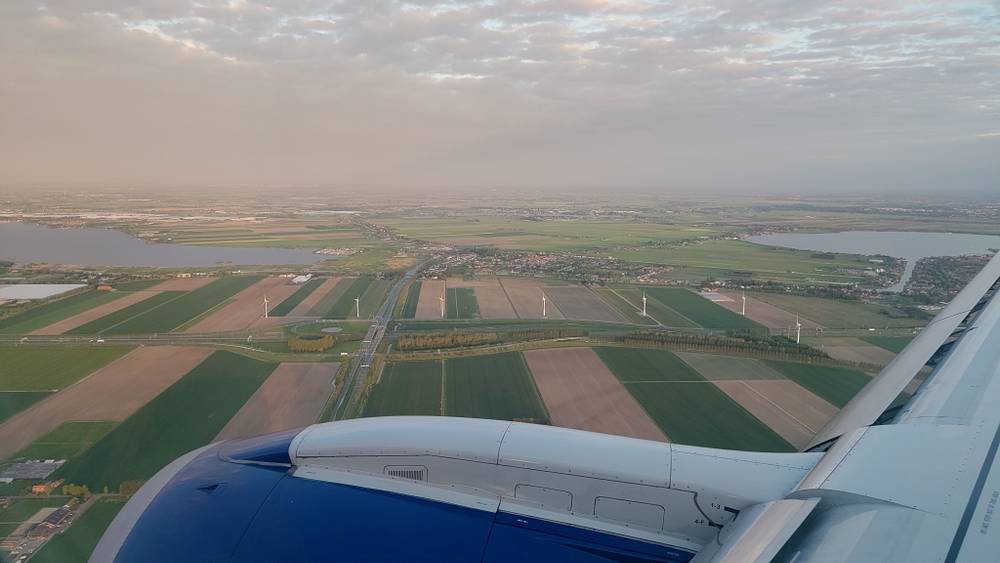 Aerial view from an airplane window over fields and waterways at dusk.
