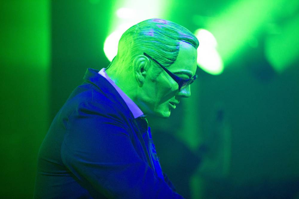A man in a suit, lit entirely green, DJs at the TNW Europe closing party.