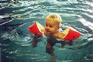 A child wearing red armbands swimming in a pool.