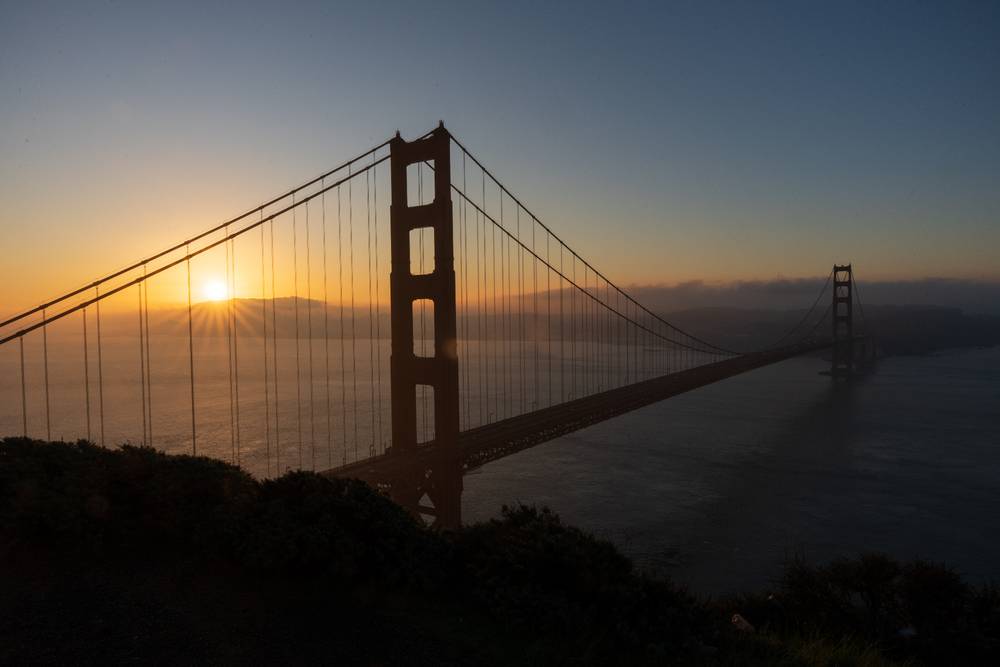 The sun rising behind the golden gate bridge 