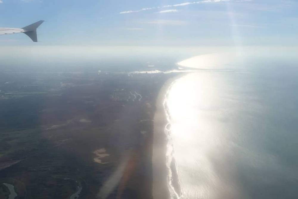 Aerial view of the sea meeting the coast, sunlight reflecting off the water.