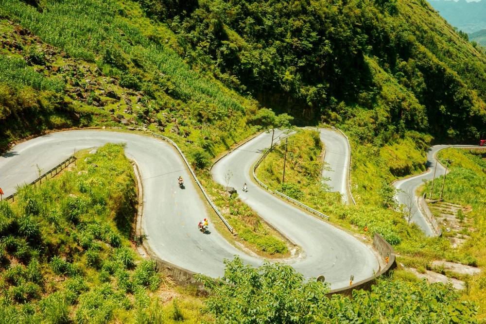 a windy mountain road with motorcyclists on it
