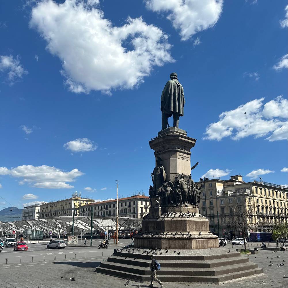 A picture of a statue in a square in Naples, outside the train station