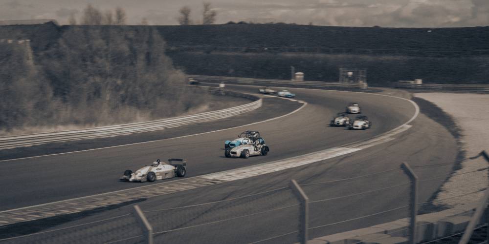 A few racing card driving and overtaking each other. A black and white image.