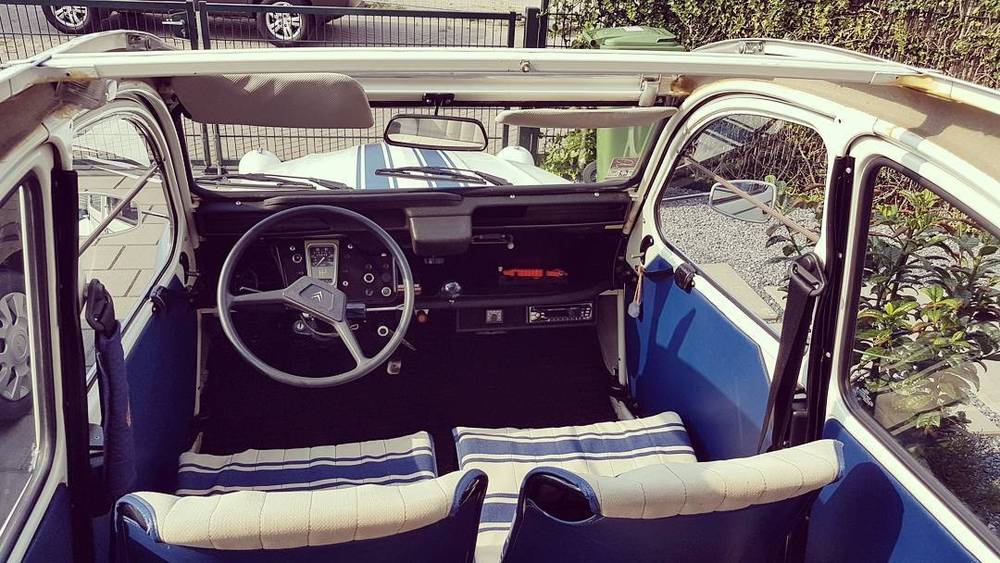 Interior view of a Citroën 2CV showing its blue and white striped seats and steering wheel.