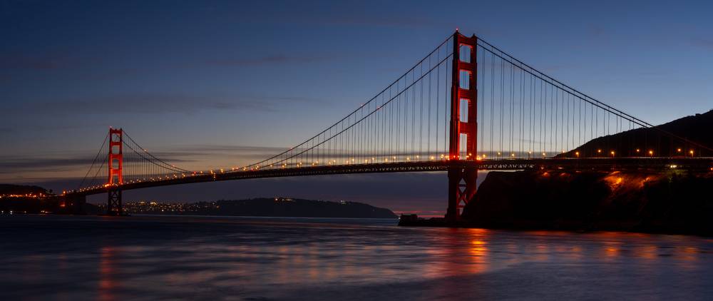 The golden gate bridge from below just as the final light of the day fades