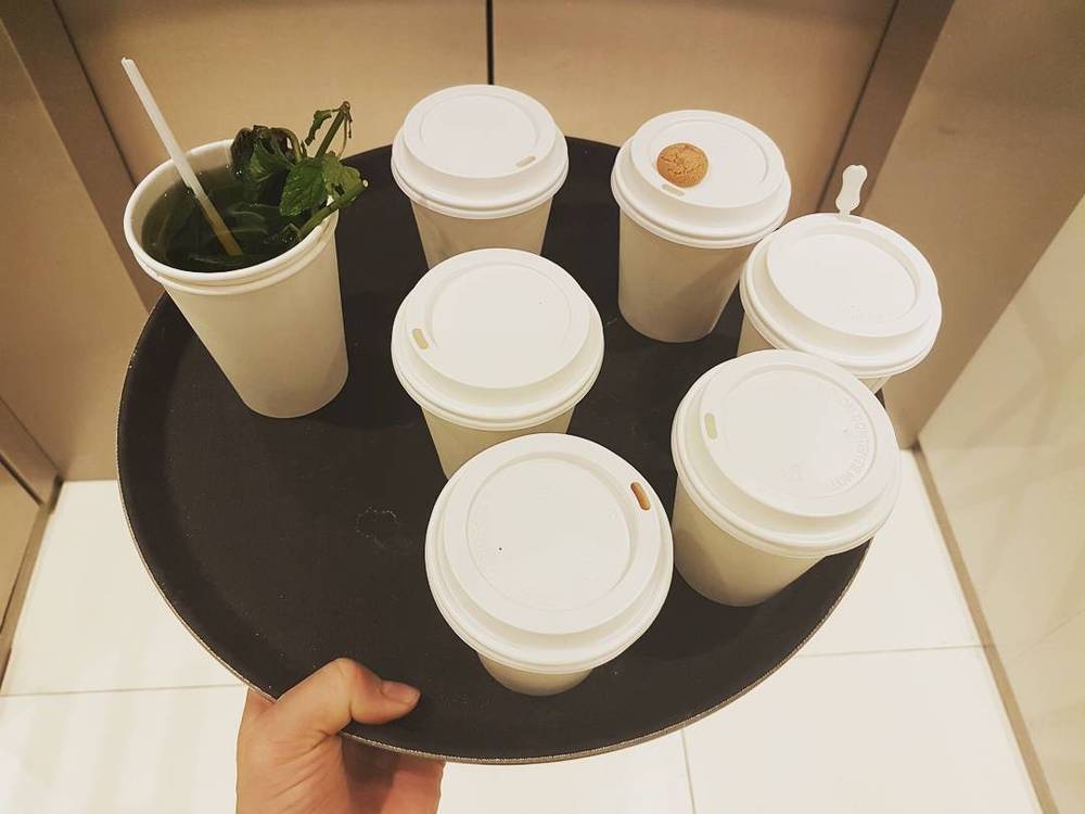 A hand holding a tray of takeaway coffee cups.