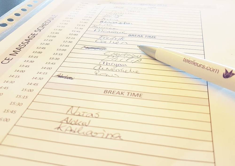 A handwritten weekly massage appointment schedule on a notepad with a pen resting on it.