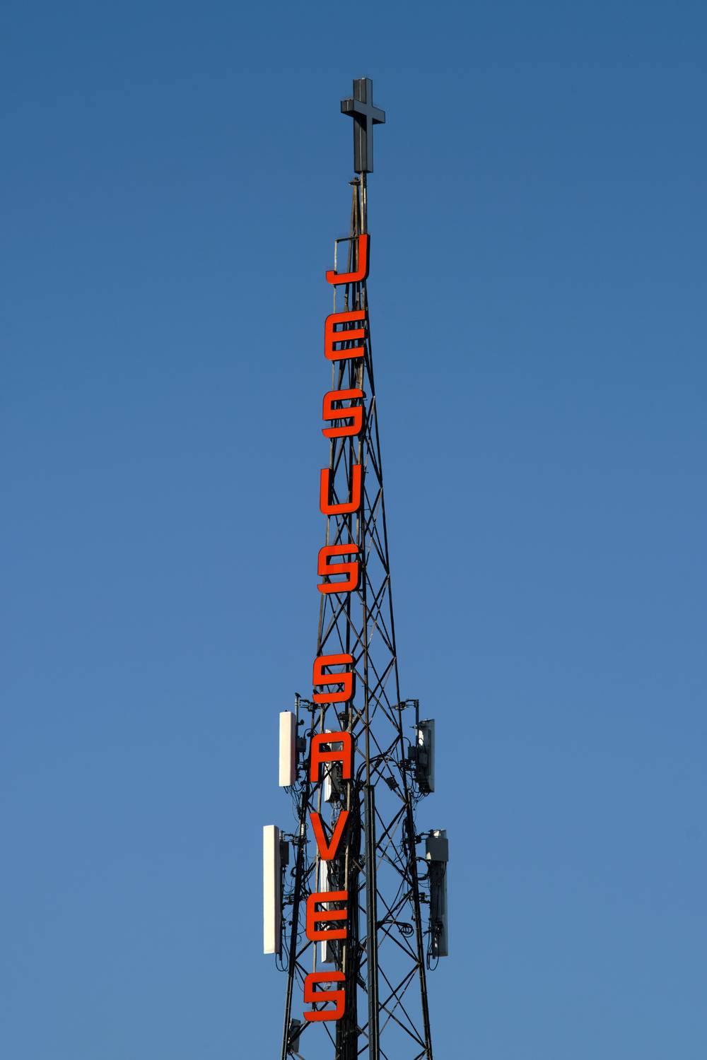 A cell phone tower with red letters "JESUS SAVES" and a cross on top. east oakland, ca