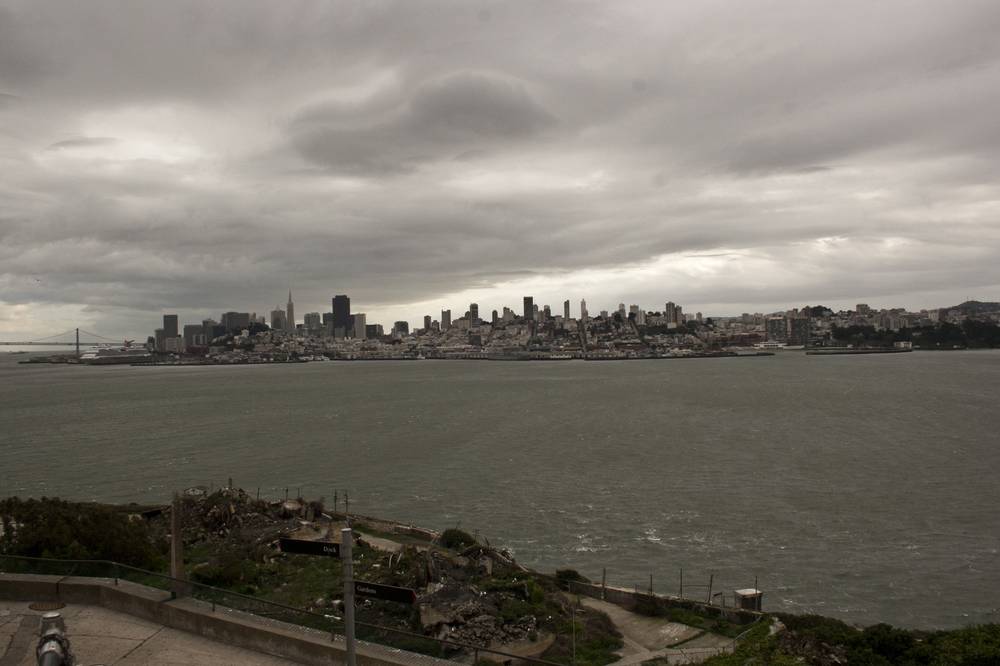 The San Francisco skyline rises across the bay, seen from Alcatraz's ruins.