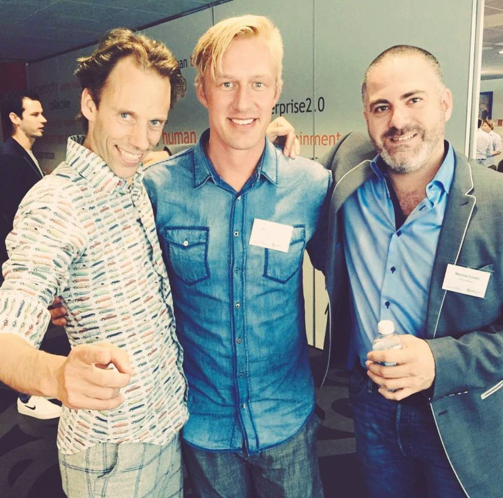 Three men posing together and smiling at a conference networking event.