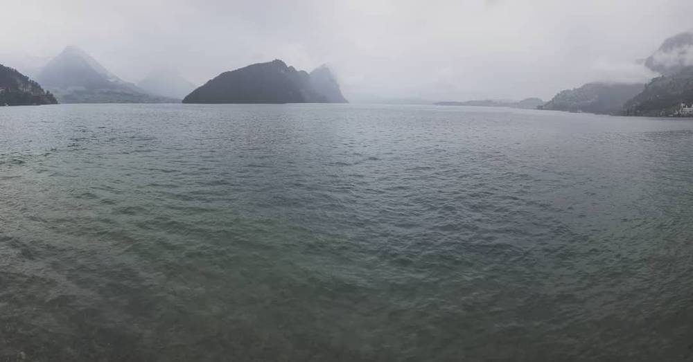 A foggy lake surrounded by mountains in muted colors.